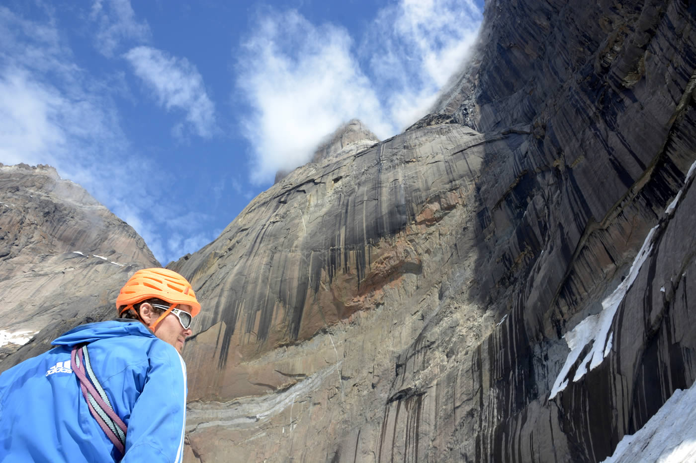 Christian Laddy Ledergerber stands at the foot of the huge overhang in the middle of the wall, with the summit in the clouds. [Photo] Silvan Schuepbach