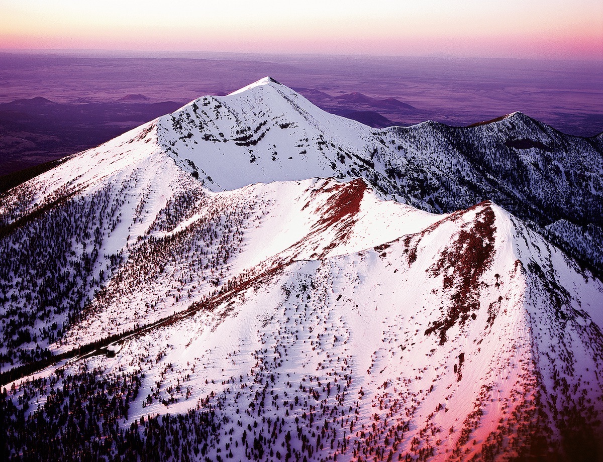 Pictured here at sunset, Dook'o'oosliid, or Humphreys Peak (12,633'), is the highest point in Arizona. Dook'o'oosliid was once part of a much larger stratovolcano that erupted hundreds of thousands of years ago. [Photo] Chuck Lawsen