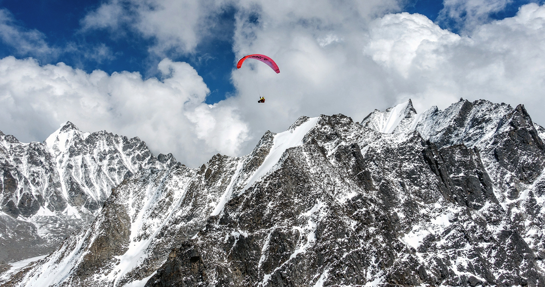 A view during the French climbers' trek to the Langtang Valley. The paraglider is a little east of the village of Sherpangau. The French bypassed three days of trekking with two hours of flying, albeit not without difficulty: On their first launch attempt they landed 400 meters lower than they had started. The conspicuous pointed rock and snow peak on the left is Peak 5857m. The rocky foreground ridge culminates in unnamed Peak 5613m. [Photo] Dusserre/Girard Collection