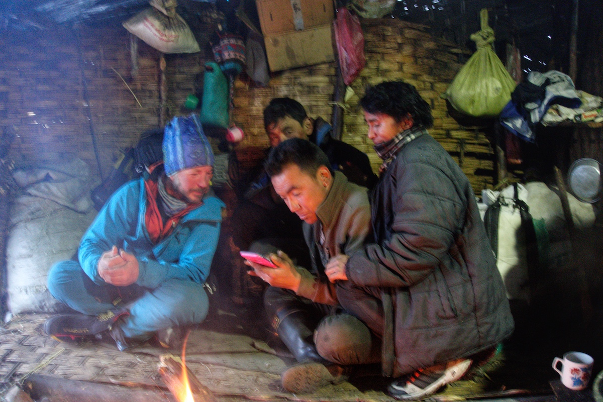 Kelley shows some pictures on his phone to some yak herders on the way down to Kathmandu. [Photo] Benjamin Billet
