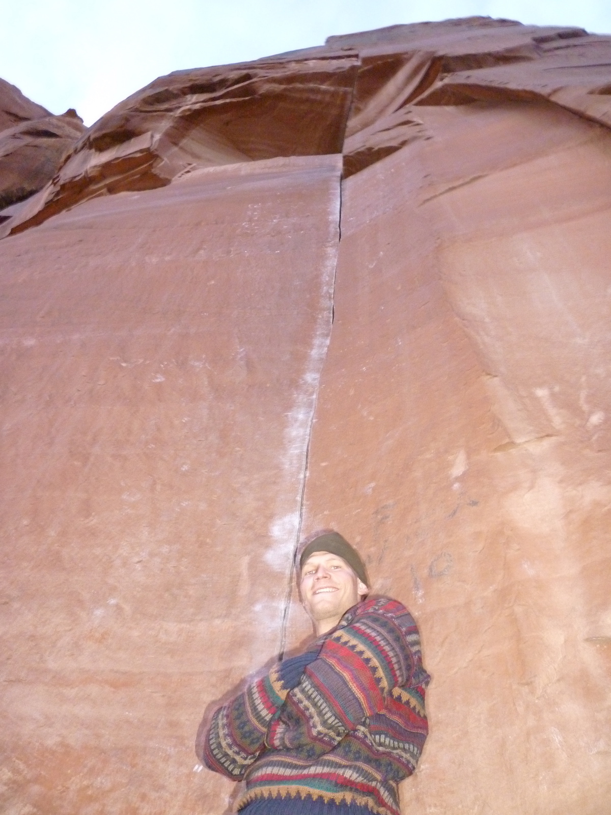 Post-send pose: the author stands under Ruby's Cafe (5.12+) in Indian Creek, 2009. Note the continuous white line of chalk along the crack. [Photo] Mandi Franz