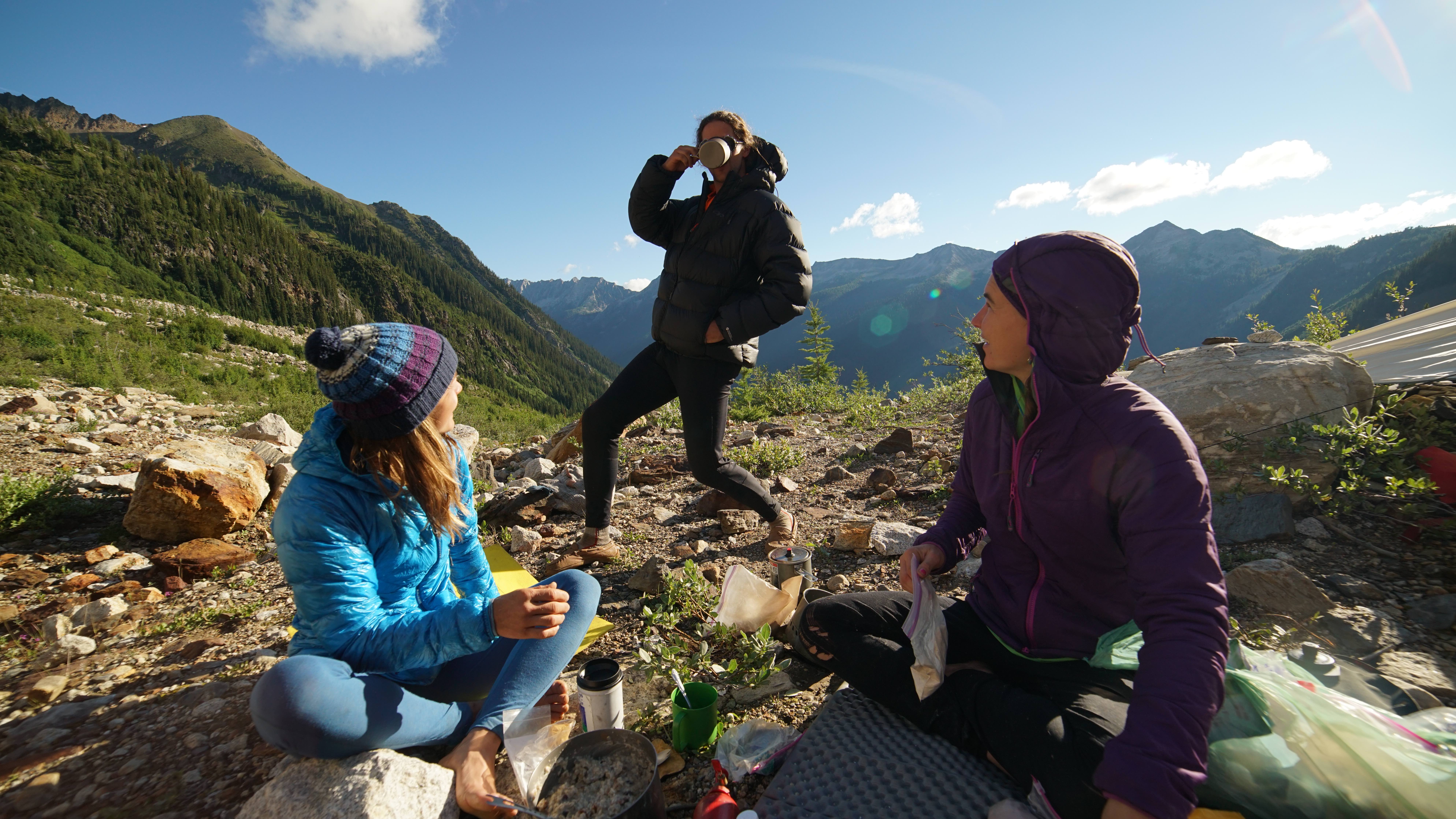 Jenny Abegg and Alix Morris look on as Forest Woodward gets enthusiastic about his morning coffee in basecamp. [Photo] Graham Zimmerman