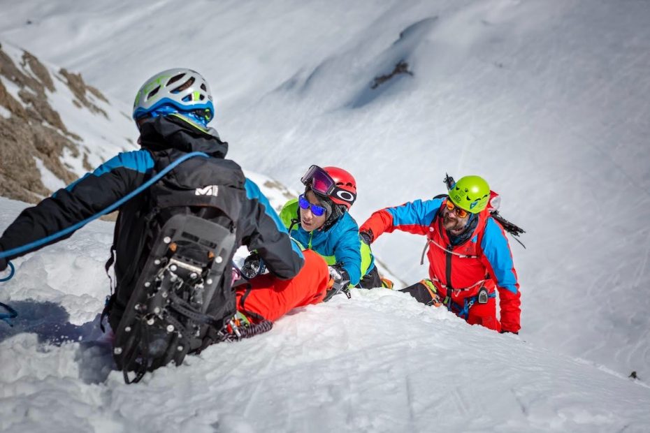 Getulio Felipe reaches the end of the via ferrata, which is buried in snow, on Punta Penia's Normal Route, Marmolada, Dolomites, Italy. He is belayed by guide Alessio Nardelotto with his friend Pedro McCardell offering support from behind. [Photo] Stefano Fabris