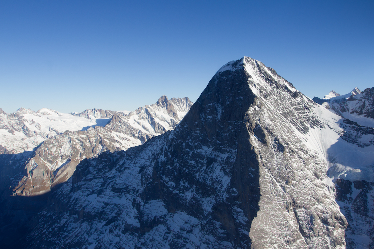 This aerial shot shows the magnitude of the Eiger North Face (3970m). Metanoia (VII 5.10 M6 A4, 1800m) takes a central line up the shadowy face. [Photo] Archive Metanoia