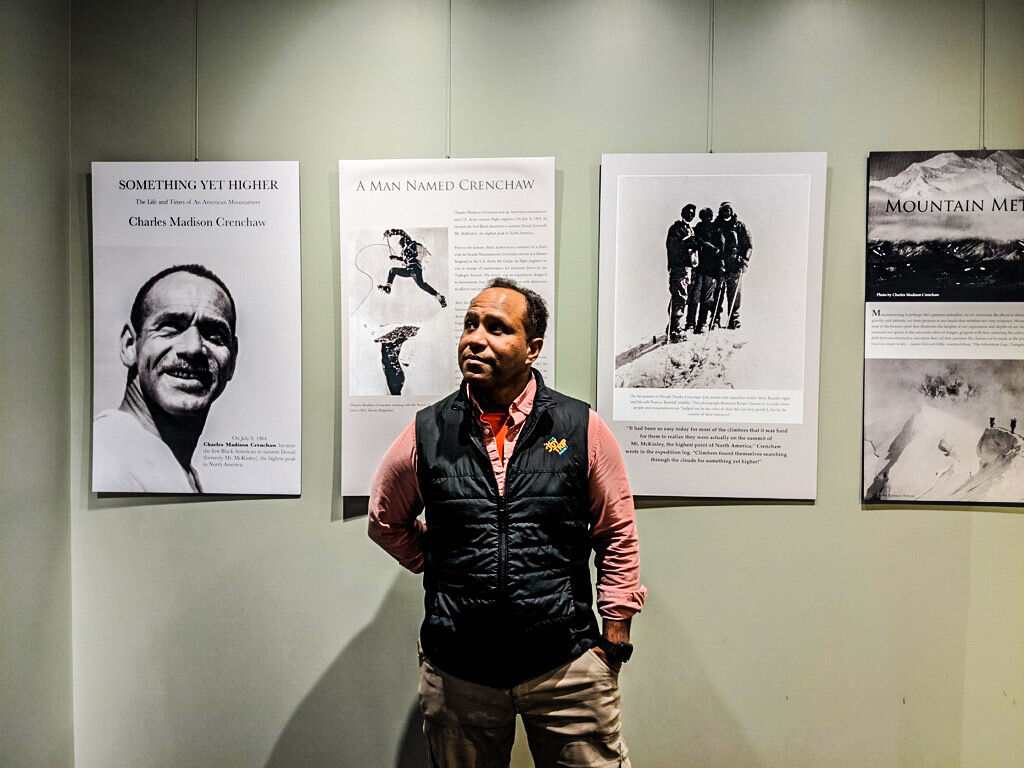 James Edward Mills stands in front of his exhibit featuring African American mountaineer Charles Madison Crenchaw at the Bradford Washburn American Mountaineering Museum, in Golden, Colorado. [Photo] Courtesy of James Edward Mills