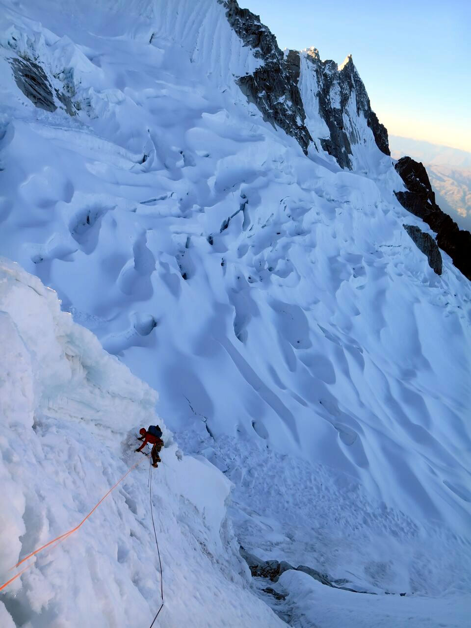 Ben Dare traversing around Taulliraju's southeast ridge with the Taulliraju Glacier below. The following day, the team dropped onto the glacier and traversed under the rock in the top right of this photo to gain the East Face Rock Rib. [Photo] Steve Skelton