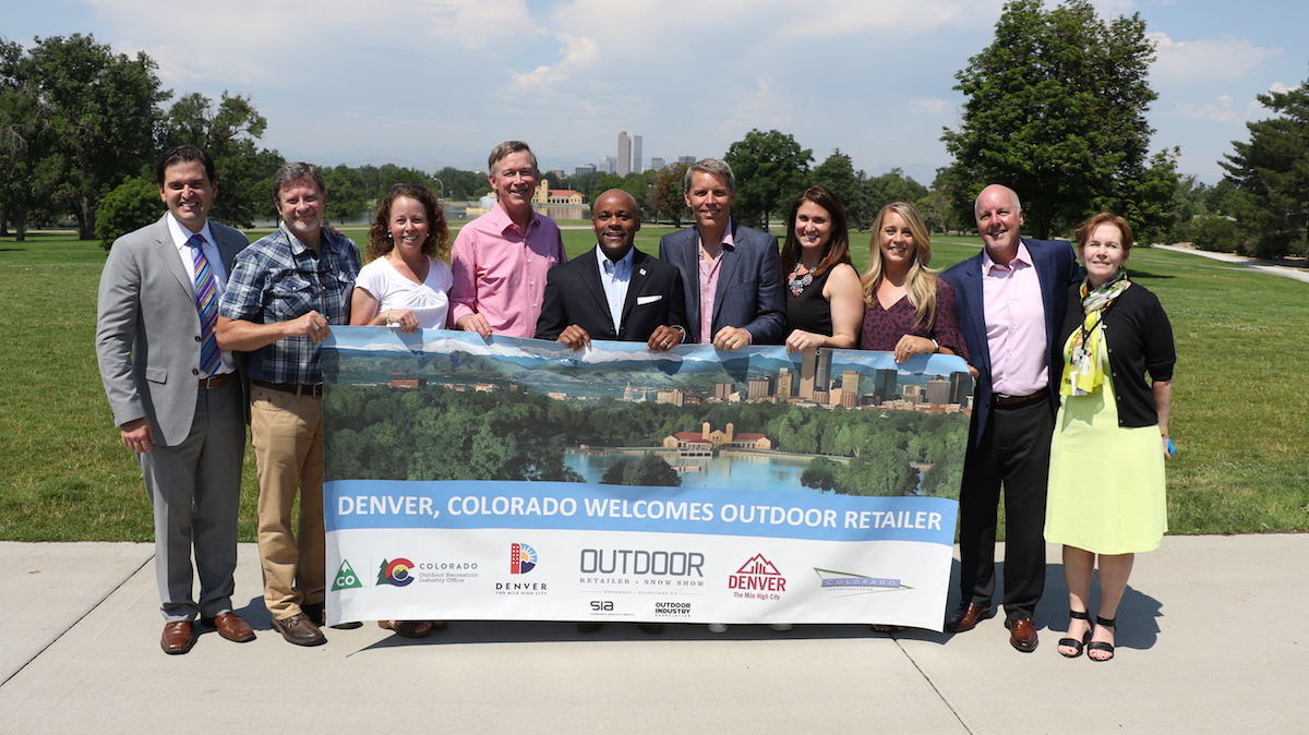 A deal was confirmed today that the summer Outdoor Retailer trade show will move to Denver, Colorado, next year. Pictured from left to right are Luis Benitez, director of Colorado's Outdoor Recreation Industry Office; Darrell Denny, executive vice president of Emerald Expositions; Amy Roberts, executive director, Outdoor Industry Association; Governor John Hickenlooper; Mayor Michael Hancock; Nick Sargent, president of SnowSports Industries America; Rachel Benedick, VP sales and service, Visit Denver; Marisa Nicholson, Outdoor Retailer show director; Richard Scharf, president and CEO, Visit Denver; Lieutenant Governor Donna Lynne. [Photo] Courtesy of Ground Floor Media