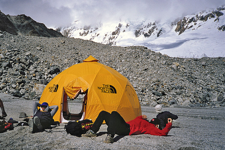 Mark Holbrook (left) and Hans Saari dozing at the advanced base camp.  The slopes where Lowe and Bridges were killed are the large, open glaciers and the avalanche came down from the peaks in the clouds. [Photo] Andrew McLean