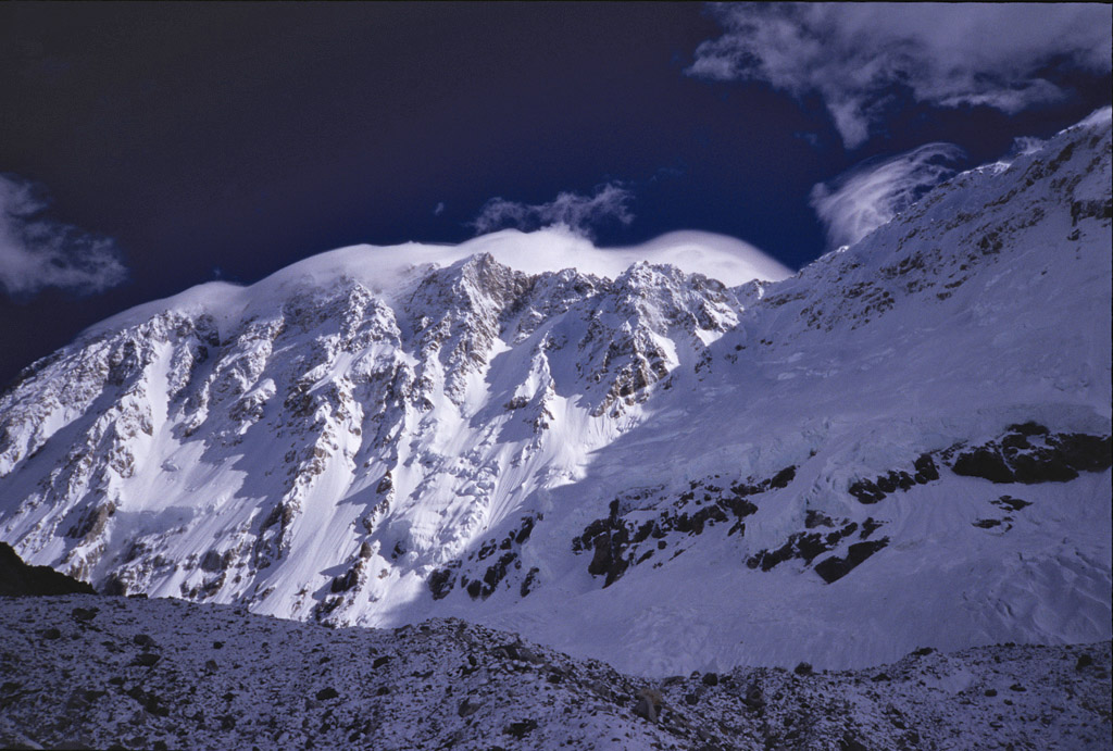 The southwest face of Shishapangma. The summit has a lenticular cloud on it, and the slopes that avalanched are the ones in the shade off to the right with the cliff bands. McLean was standing on top of the moraine looking down and into the hidden valley on the other side. [Photo] Andrew McLean